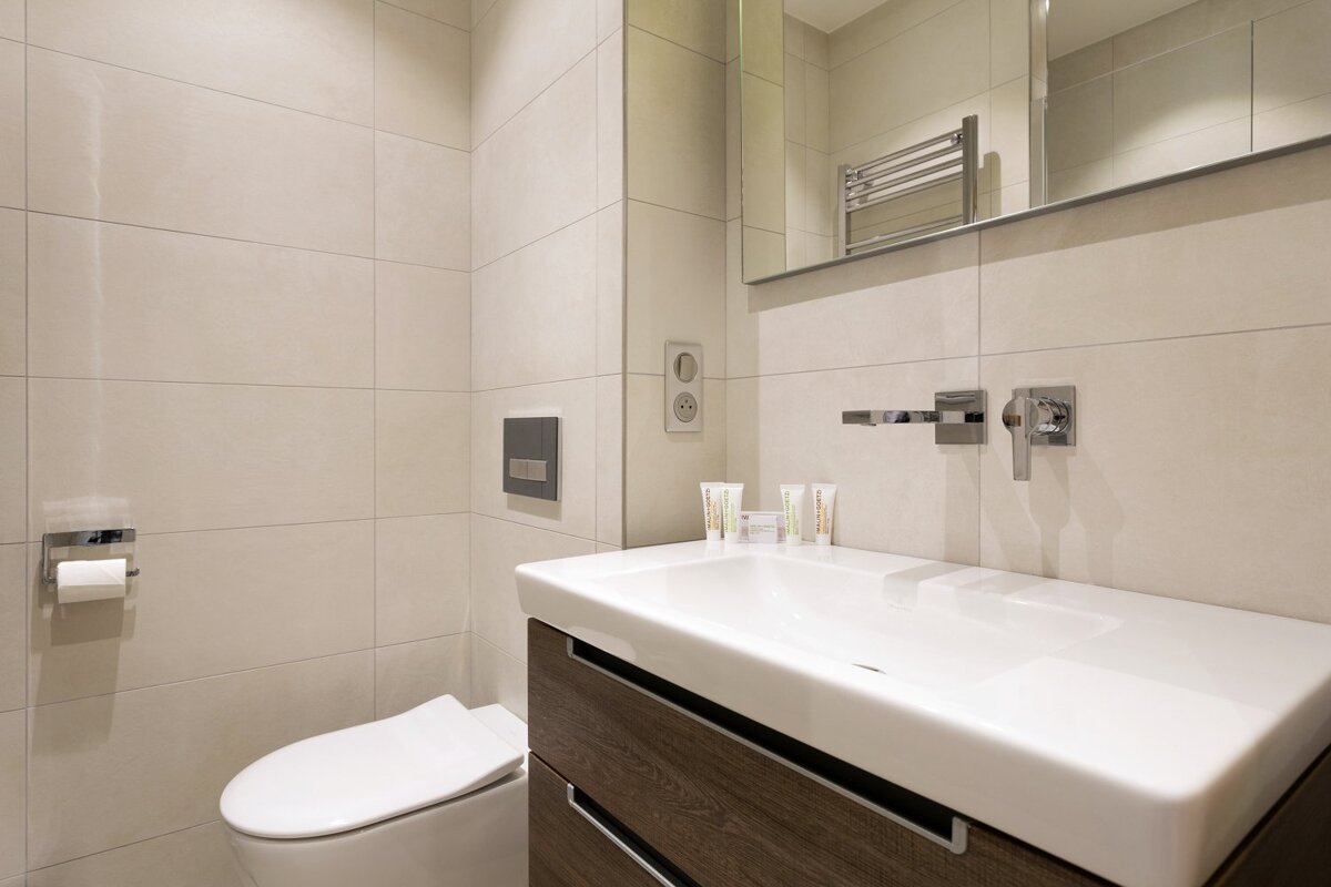 A bathroom with a toilet a sink and a mirror
