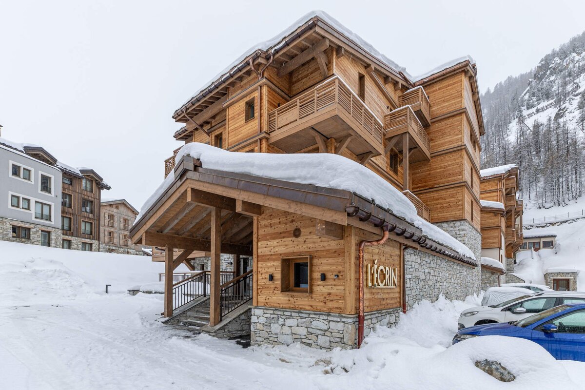 A large, snow-covered luxury wooden chalet building (