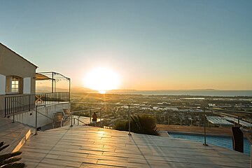 The sun is setting over the ocean from a balcony