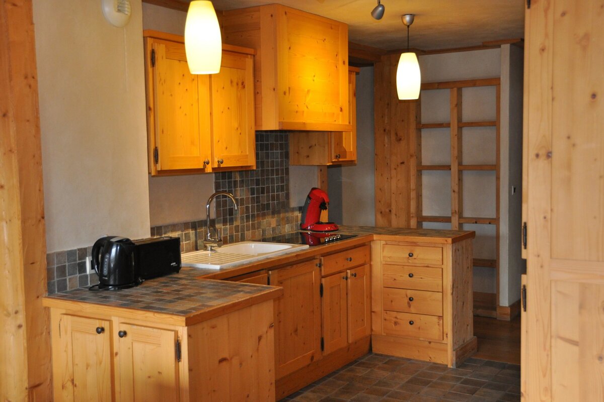 A kitchen with wooden cabinets and a red coffee maker