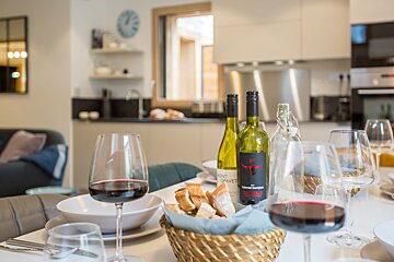 A bottle of mont grave wine sits on a table next to a basket of bread