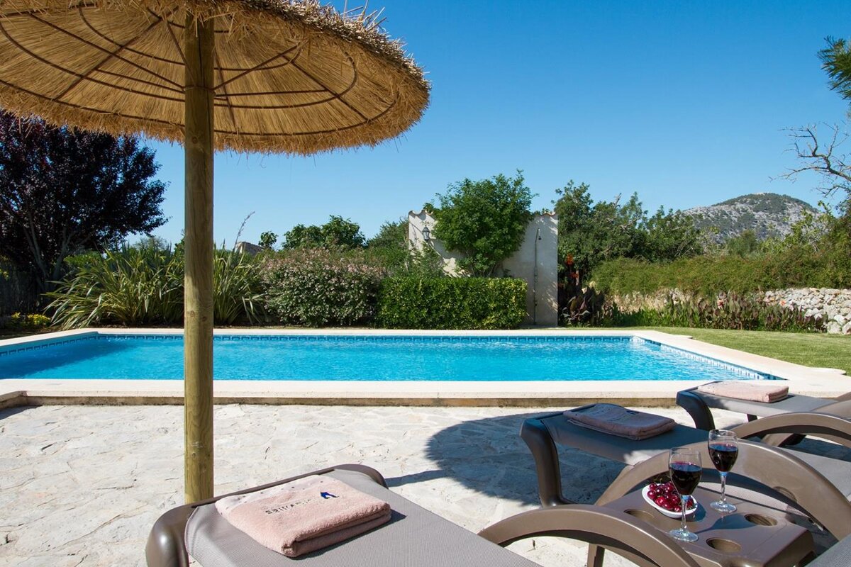 A swimming pool with a thatched umbrella and chairs