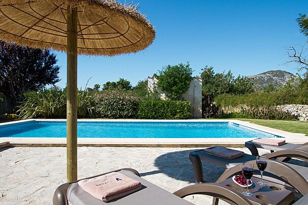 A swimming pool with a thatched umbrella and chairs
