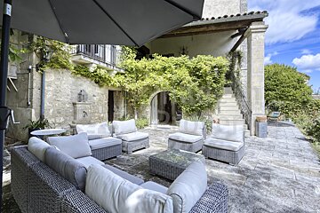 A patio with a couch and chairs under an umbrella that says ' immobilier ' on it