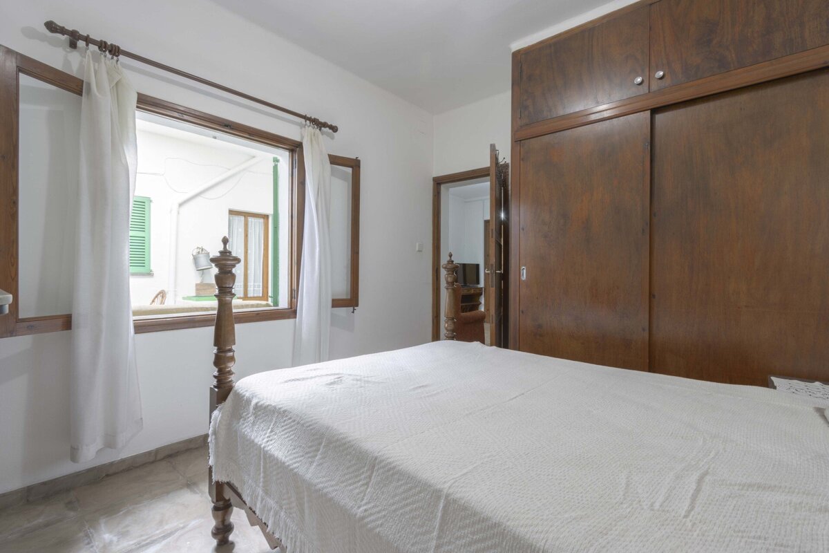 A bedroom with a bed and a window with green shutters