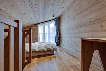 A wooden room with a bed and a window
