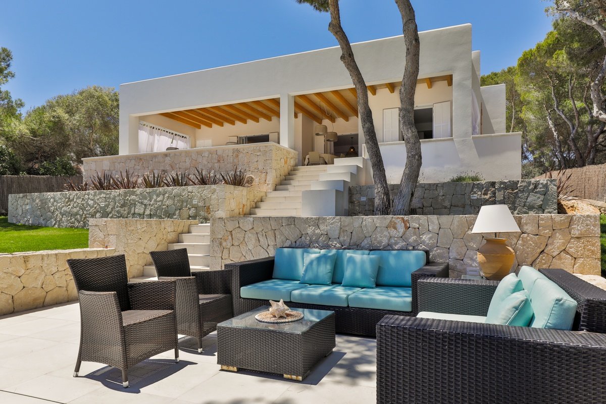 A patio area with a couch and chairs in front of a house