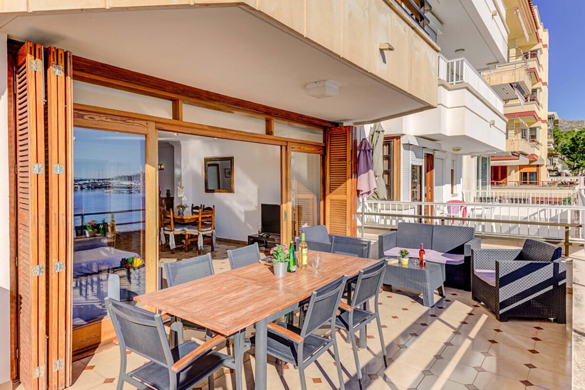 A table and chairs on a balcony with a view of the ocean