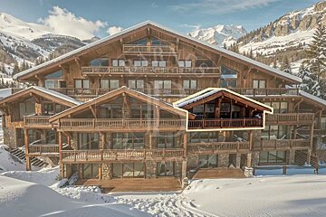 A large wooden mountain chalet in a snowy landscape with one balcony highlighted by a yellow outline.
