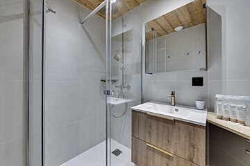 A bathroom with a walk in shower and a sink