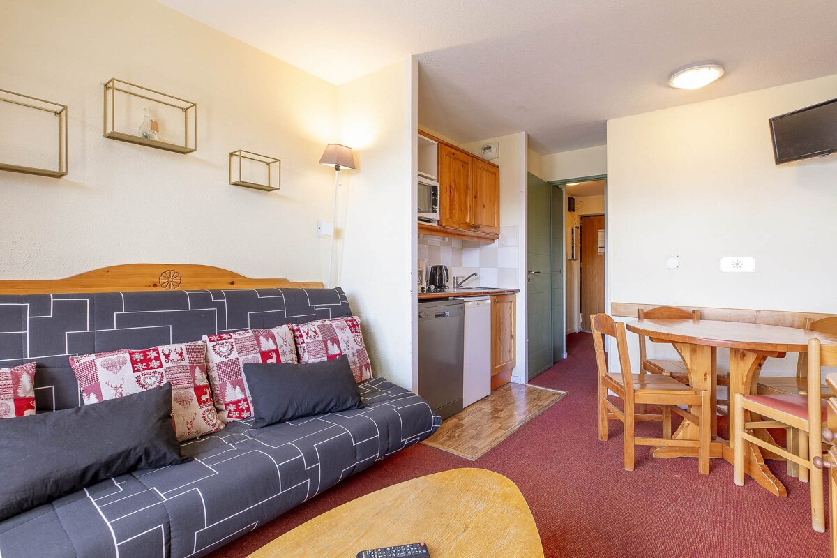 A living room with a red couch and wooden table