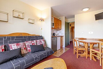 A living room with a red couch and wooden table