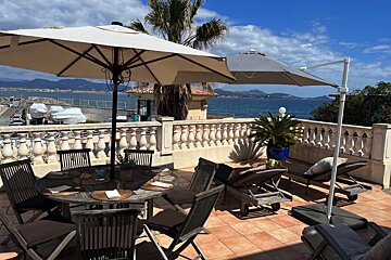 A table and chairs on a balcony overlooking the ocean