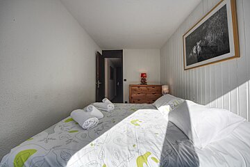 A small bedroom with a bed and a dresser