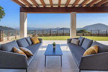 A patio with a couch and a table with mountains in the background