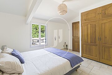 A bedroom with a bed and a window with the letter j on the wall