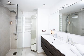 A bathroom with a walk in shower and a sink