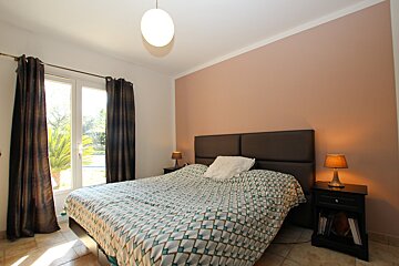 A bedroom with a large bed and two lamps