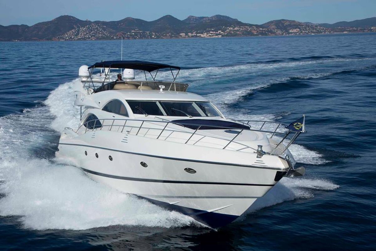 A white yacht is going through the ocean with mountains in the background
