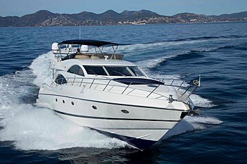 A white yacht is going through the ocean with mountains in the background