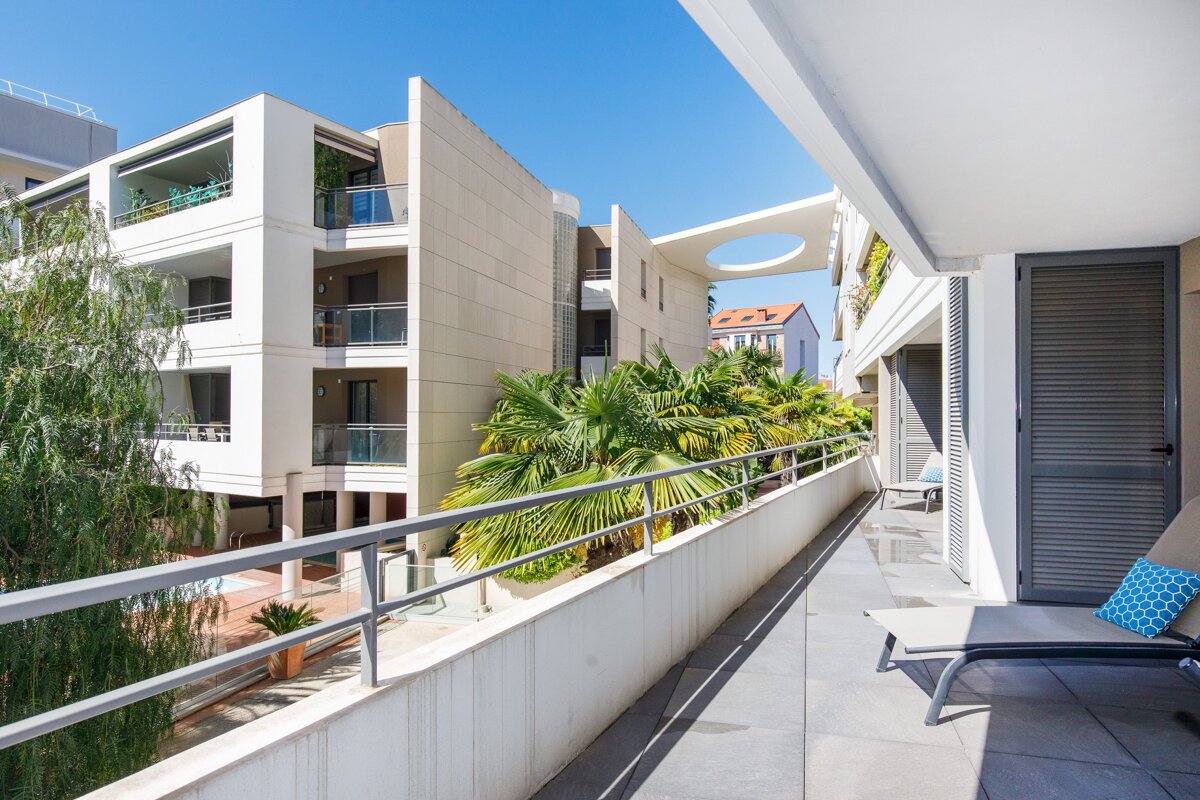 A balcony in front of a building with palm trees