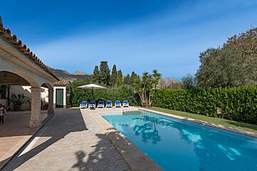 A swimming pool with blue chairs and an umbrella