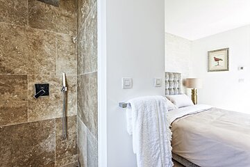 A bedroom with a walk in shower and a bed