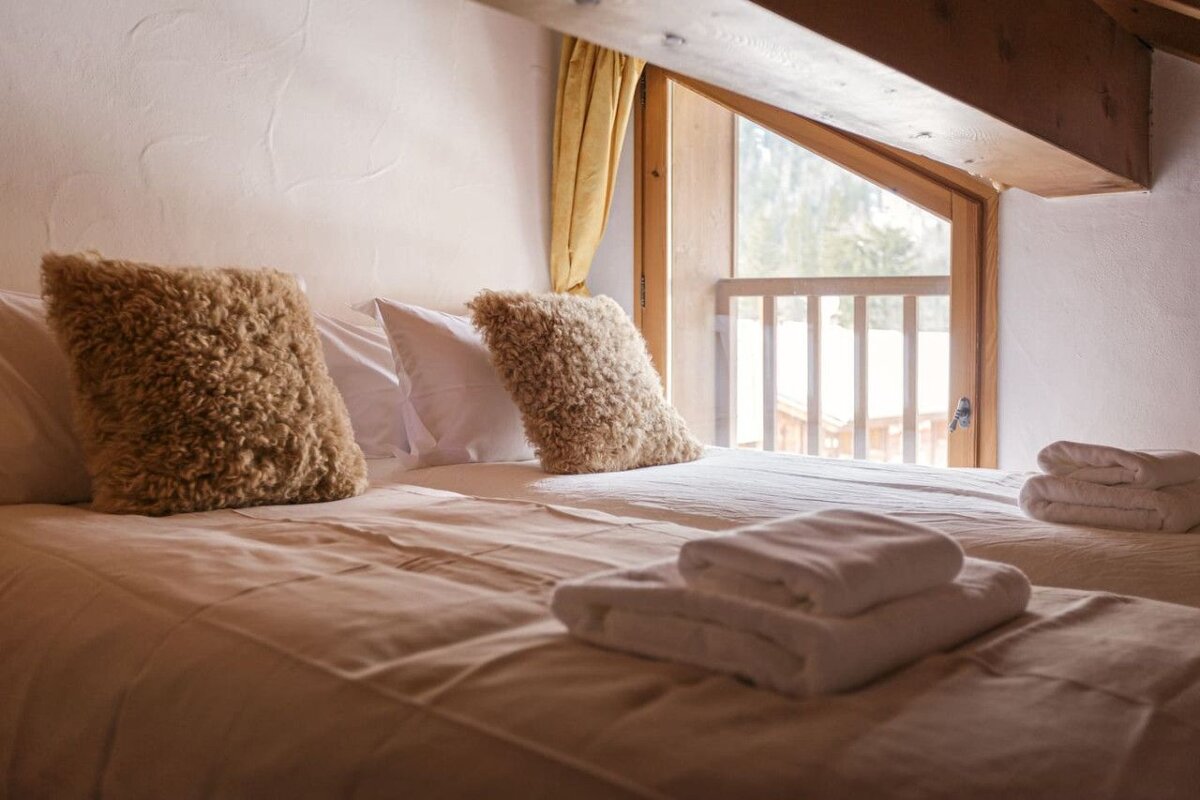 A bed with pillows and towels in front of a window