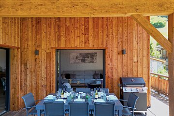 A dining table and chairs outside of a wooden house