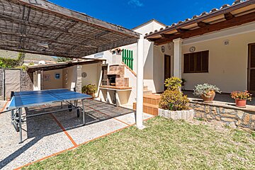 A ping pong table sits under a canopy in front of a house