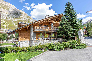 A large wooden house with a mountain in the background