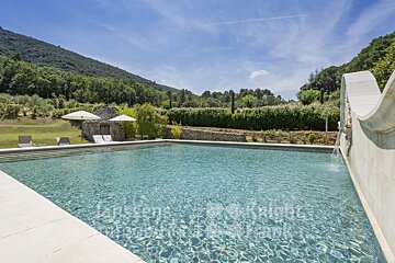 A large swimming pool is surrounded by a stone wall