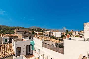 A rooftop view of a small town with mountains in the background