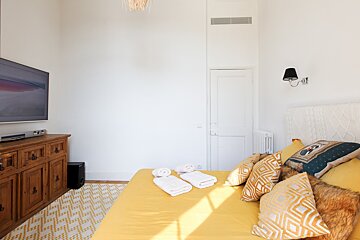 A bedroom with a large flat screen tv above the bed