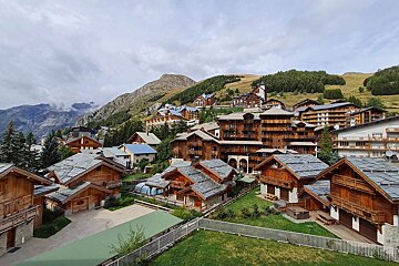 A row of houses on a hillside with mountains in the background