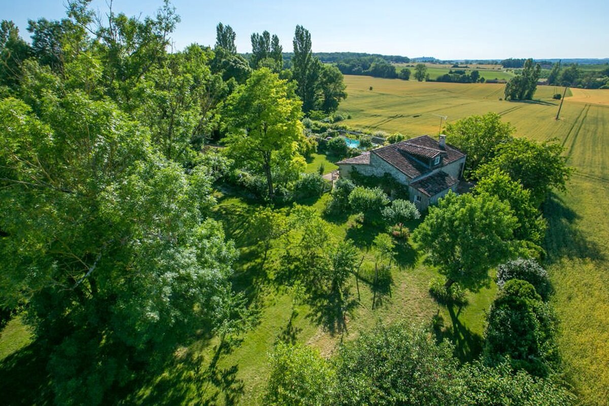 An aerial view of a house surrounded by trees and grass