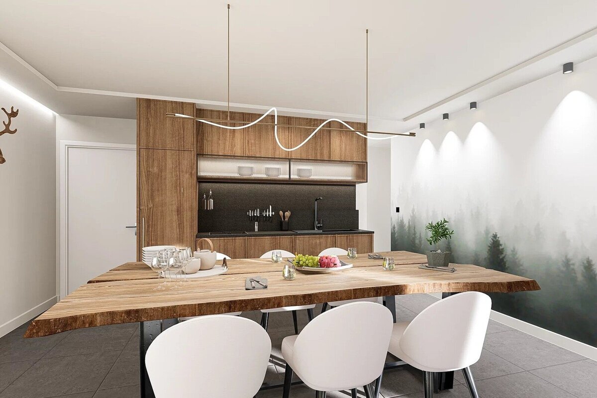 A modern kitchen/dining area with a live-edge wood table, white chairs, sleek wooden cabinetry, and a black counter. A forest mural adorns one wall.