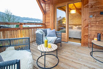A balcony with a chair a table and a bottle of orange juice