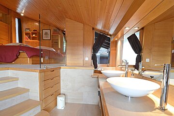 A bathroom with two sinks and a bed in the background