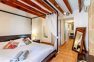 A bedroom with a canopy bed and a mirror