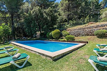 A large swimming pool surrounded by lawn chairs and trees