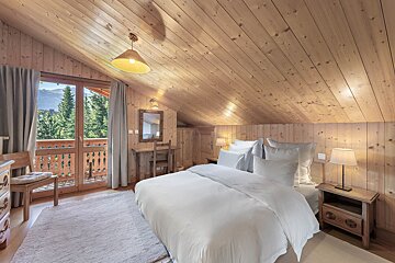 A bedroom with a large bed and a balcony
