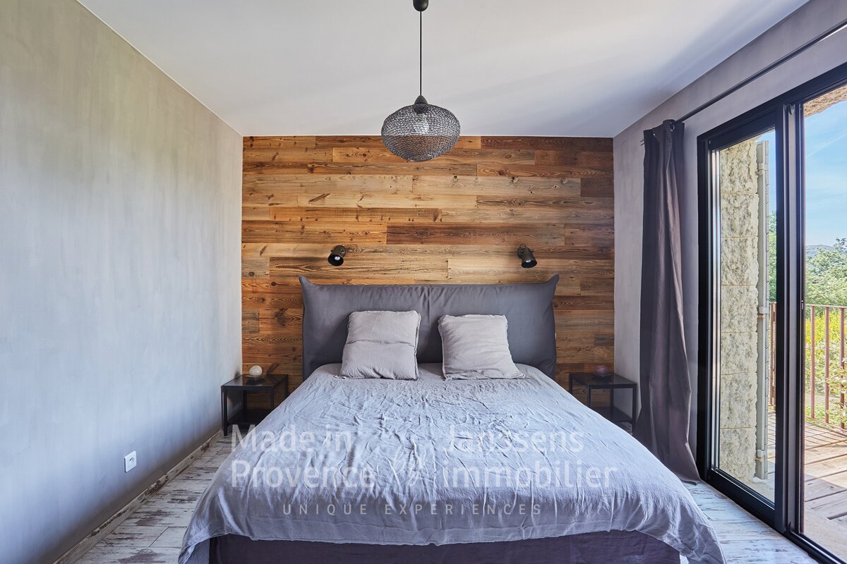A bedroom with a bed and a wooden wall made by provence immobilier