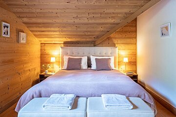 A bedroom with a wooden ceiling and a bed