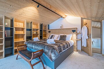 A bedroom with a king size bed and a bench