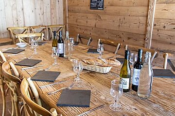 A long wooden table with wine bottles and glasses on it