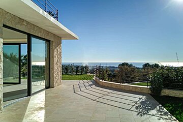 A patio with a view of the ocean and trees