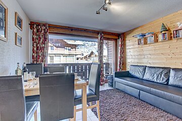 A living room with a couch a table and chairs and a balcony