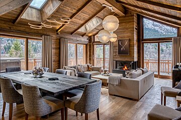 A living room with a wooden table and chairs and a fireplace