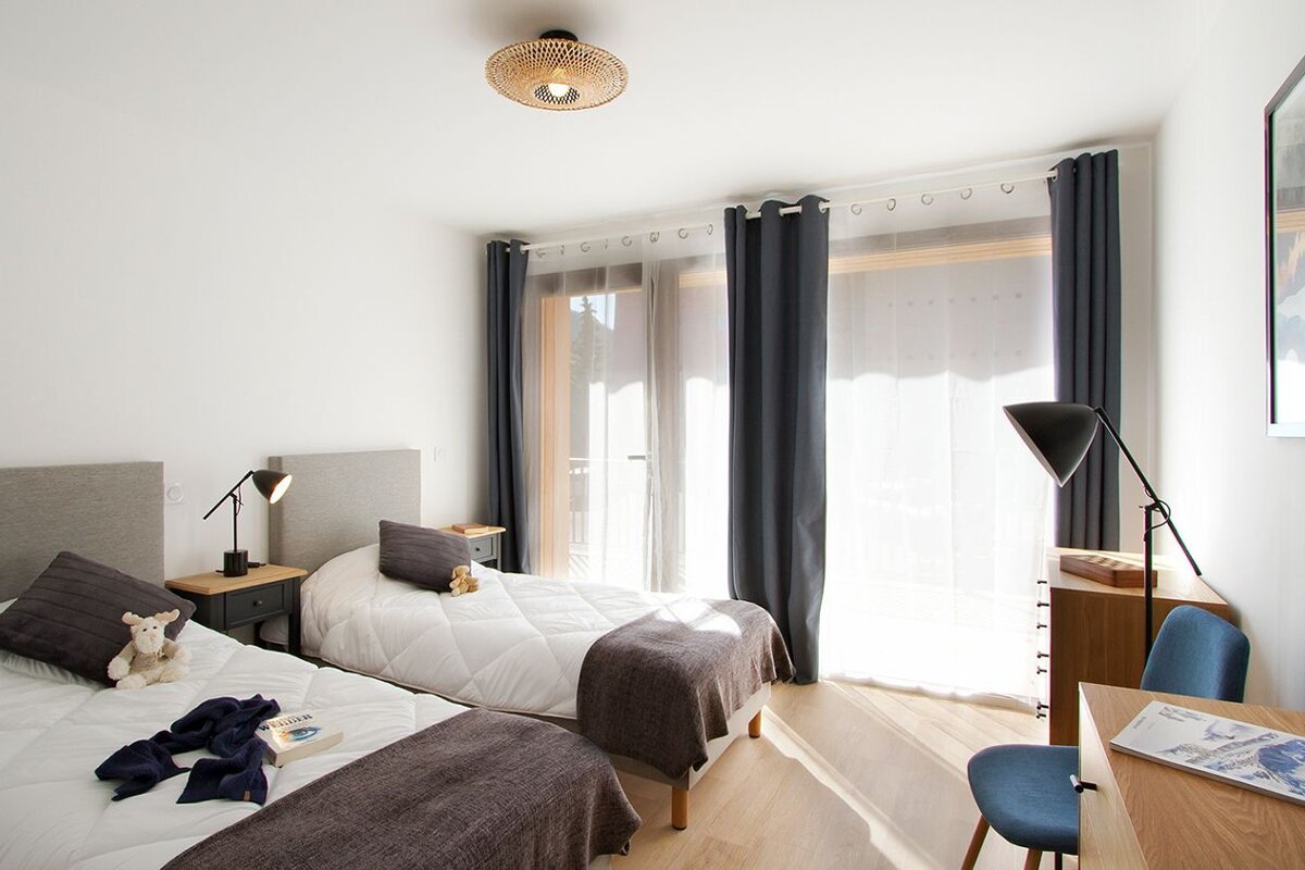 A bedroom with two beds and a desk with a magazine on it